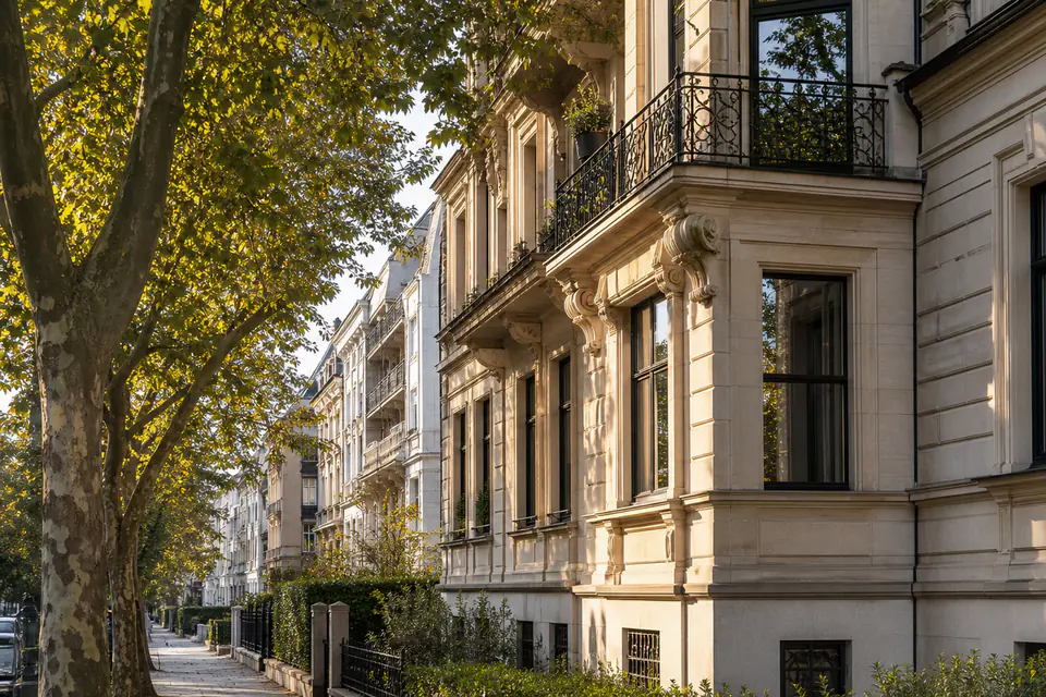 Helle Westend-Altbauzeile mit Baumkronen und zurückhaltender Tiefe.