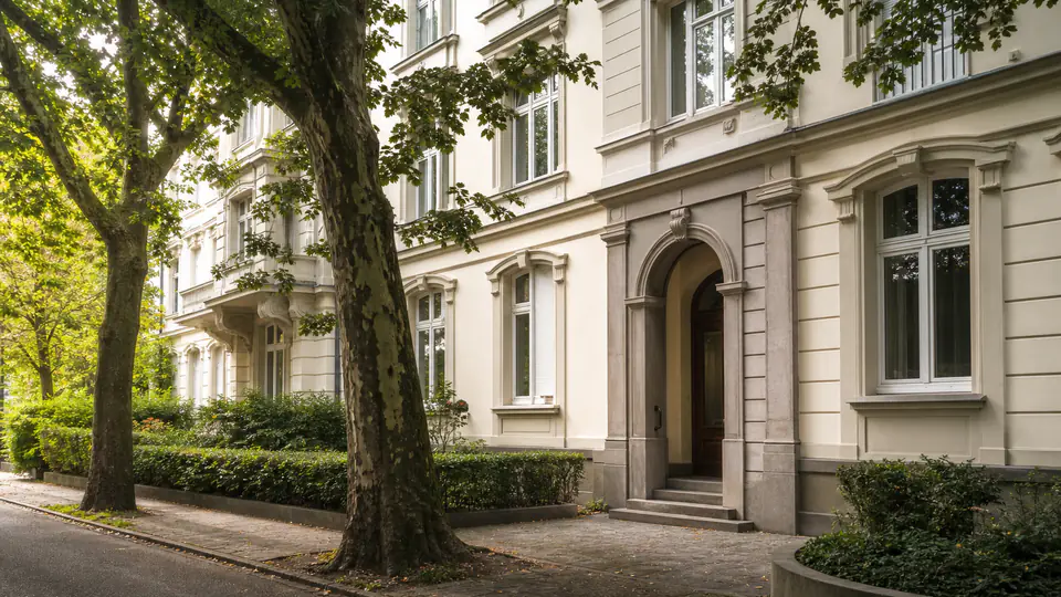 Gepflegte, klassische Frankfurter Wohnfassade unter altem Baumbestand.